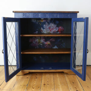 Blue Cabinet with glass doors open to reveal floral interior and wooden shelves