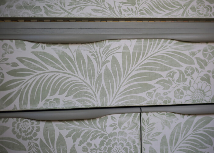 Close up of distressed floral detailing on green teak bureau desk