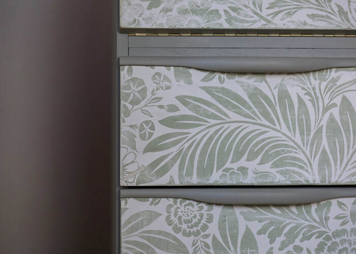 Close up of distressed floral detailing on green teak bureau desk