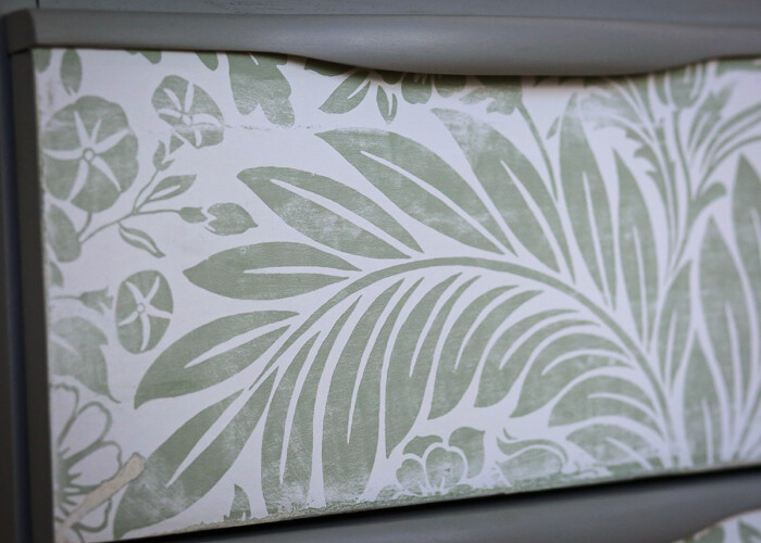 Close up of distressed floral detailing on green teak bureau desk