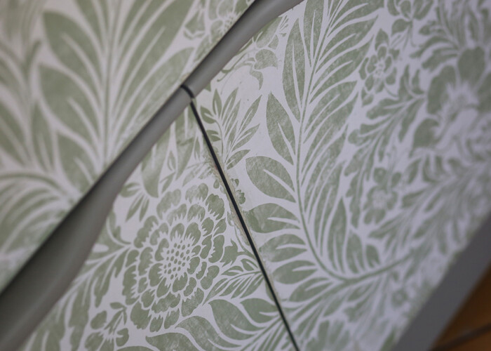 Close up of distressed floral detailing on green teak bureau desk